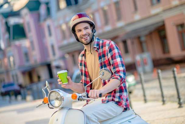 Smiling man having a morning coffee while riding to work - 写真・画像