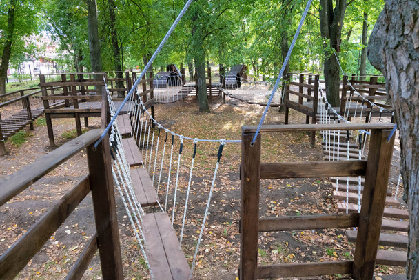 rope Park for children in the green forest. The bridge of logs tied to the ropes. Autumn park. painted wooden boards - Фото, зображення