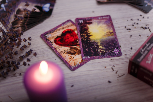 Tarjetas de adivinación alineadas con vela ardiente púrpura y lavanda seca. Misterio, astrología, ocultismo, adivinación y creencia. - Foto, imagen