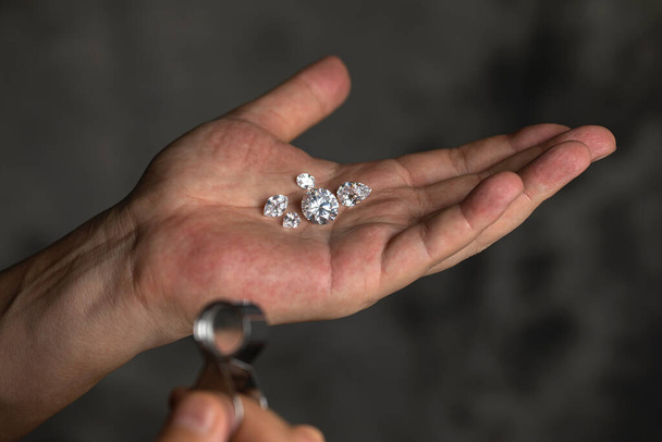 Man jeweller hand holding nice luxury diamond. Grading gem precious stones. Diamond business, industry. Gemology lab examination, expensive goods testing. - Foto, afbeelding