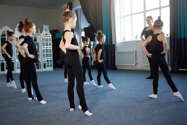 Tinédzser lányok csoportja táncból, balettból, ritmikus gimnasztikából. Fekete tornadressz, zsemlében a haj, koreográfia, figyelem, fehér zokni. Visszanézés. - Fotó, kép