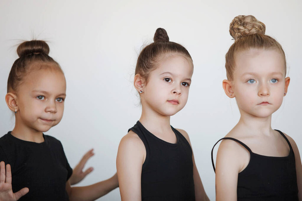 Három tinédzser lány táncból, balettból, ritmikus gimnasztikából. Fekete tornadressz, zsemlében a haj, koreográfia, figyelem. - Fotó, kép