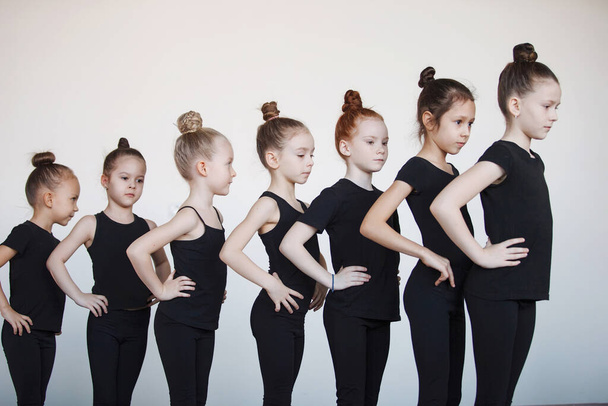 黒のレオタードの10代の女の子はダンス、バレエ、またはリズム体操のレッスンで列になっています. - 写真・画像