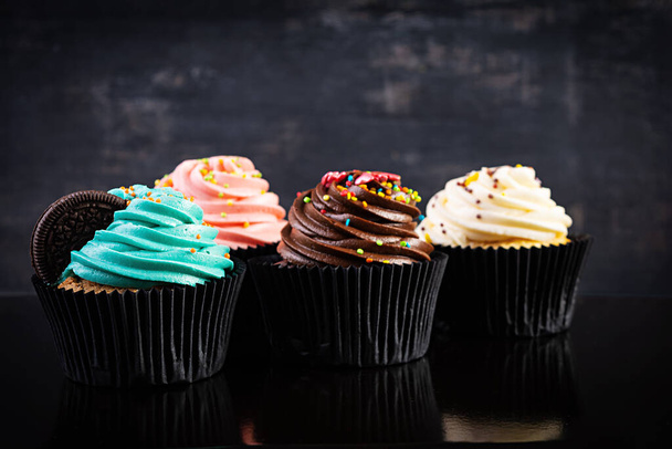 Νόστιμα πολύχρωμα cupcakes απομονωμένα σε σκούρο φόντο. Υπέροχο κεκάκι - Φωτογραφία, εικόνα