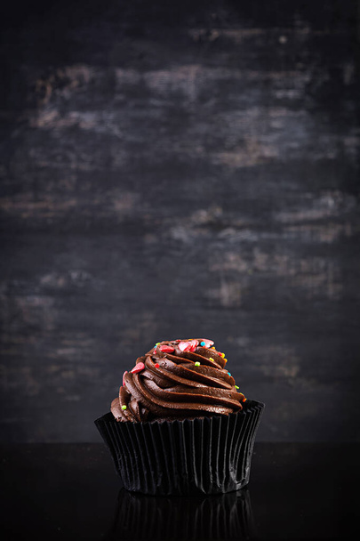 Вкусные красочные кексы изолированы на темном фоне. Вкусный кекс - Фото, изображение