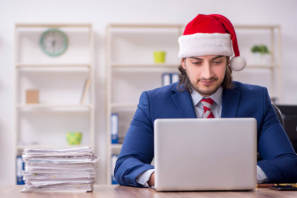 Nuori miespuolinen työntekijä työskentelee toimistossa jouluaattona - Valokuva, kuva
