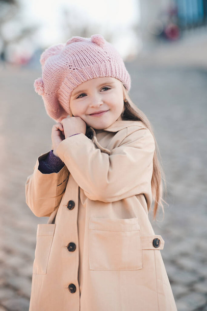 Usmívající se roztomilá holčička 3-4 roky na sobě pletený klobouk a zimní béžový kabát pózující v parku venku zblízka. Dětství. Štěstí. Podzimní období. - Fotografie, Obrázek