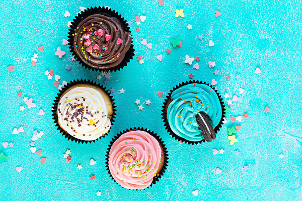 Sabrosos pastelitos de colores aislados sobre fondo azul. Delicioso cupcake - Foto, imagen