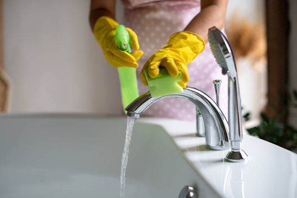 Professionelle Reinigung von Bad und Toilette. Sauberkeit und Hygiene zu Hause. Reinigung und Reinigung. Hand in Hand mit grünen und gelben Latexhandschuhen. Badezimmer und Wasserhähne reiben - Foto, Bild