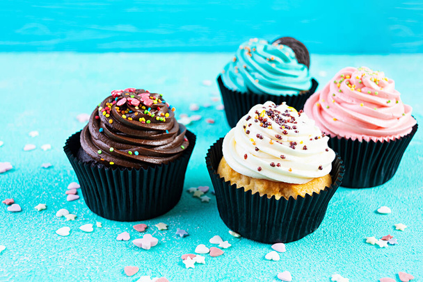 Sabrosos pastelitos de colores aislados sobre fondo azul. Delicioso cupcake - Foto, Imagen