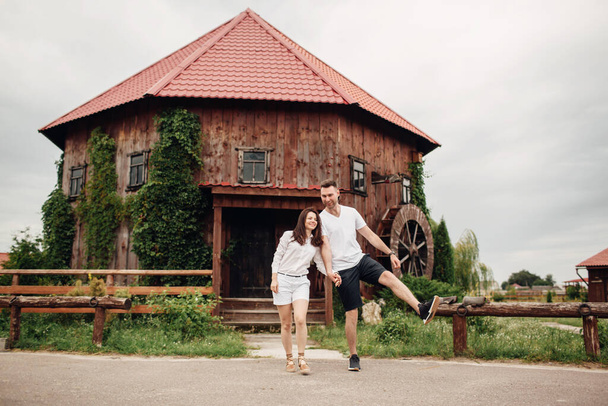 Coppia innamorata cammina vicino a un grande mulino di legno il giorno d'estate. uomo e donna si divertono all'aperto - Foto, immagini