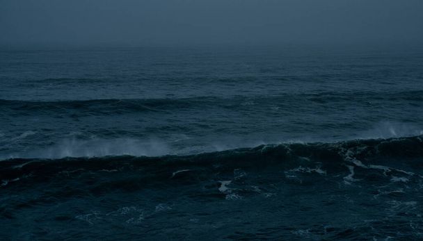 Detailbeeld van grote golven die 's nachts in de open oceaan breken tijdens een tropische storm - Foto, afbeelding