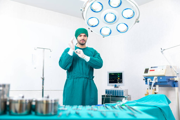 外科医は現代医療機器を備えた手術室で手袋を着用しています. - 写真・画像
