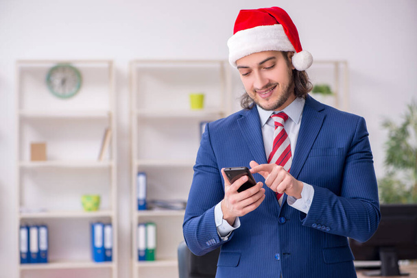 Young male employee working in the office at Christmas Eve - Foto, imagen