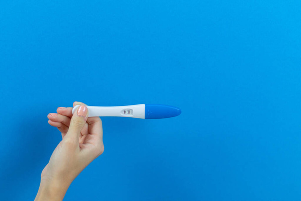 положительный тест на беременность на синем фоне в руках девушки - Фото, изображение