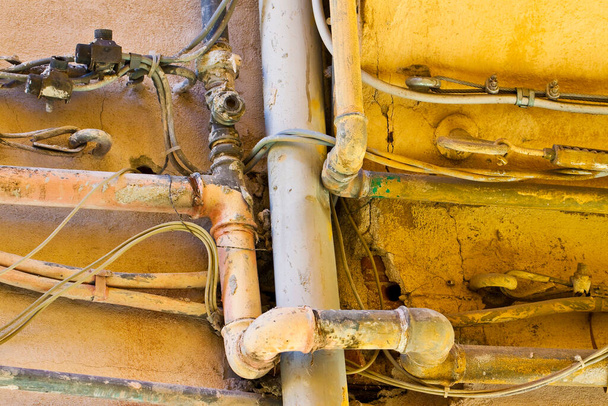 Rurociąg wodno-gazowy i kabel elektroenergetyczny przed starym murem z cegły - Zdjęcie, obraz