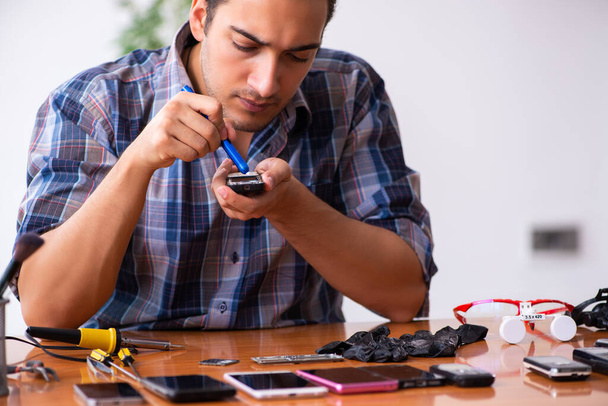Молодой техник-мужчина ремонтирует мобильный телефон
 - Фото, изображение
