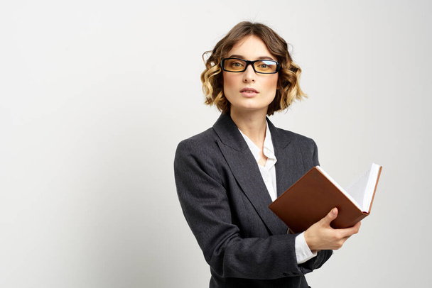 Επιχειρηματίας με κλασσικό κοστούμι με σημειωματάριο στο χέρι και γυαλιά στο πρόσωπό της. - Φωτογραφία, εικόνα