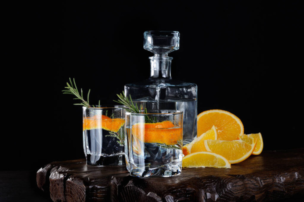 Koktél klasszikus száraz Gin-tonik és a narancs héját, egy ágacska rozmaring egy fából készült hajón lédús narancs szeletek - Fotó, kép