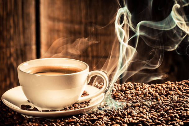 Zbliżenie prażonych ziaren z dymem i białą filiżanką kawy - Zdjęcie, obraz