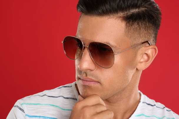 Handsome man wearing sunglasses on red background, closeup - Foto, Imagem