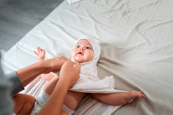 Bir anne beyaz bir bebeği bebek bezine sarar. Yukarıdan manzara. Çocuk bakımı ve çocukluk kavramı. - Fotoğraf, Görsel