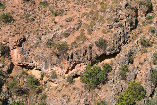 βράχος σε ένα βουνό στη νότια Ισπανία, υπάρχουν ρωγμές, υπάρχουν θάμνοι και δέντρα - Φωτογραφία, εικόνα