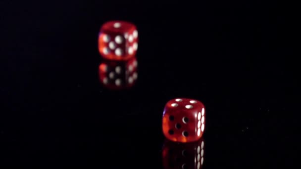 Langzame beweging van rollende spel kubussen op de zwarte tafel.Rollende rode casino dobbelstenen - Video