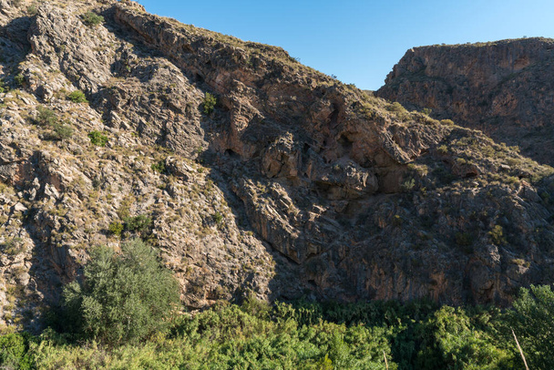 Hegyvidéki táj Dél-Spanyolországban, a hegyek sziklából vannak, vannak nád mezők és nyárfák, az ég tiszta. - Fotó, kép