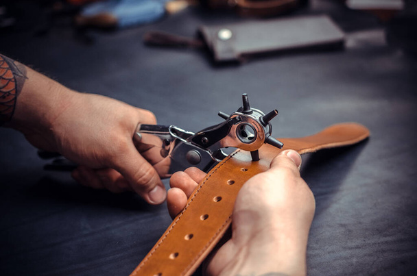 Handwerker führt Lederbearbeitung für ein neues Produkt in seiner Gerberei durch - Foto, Bild
