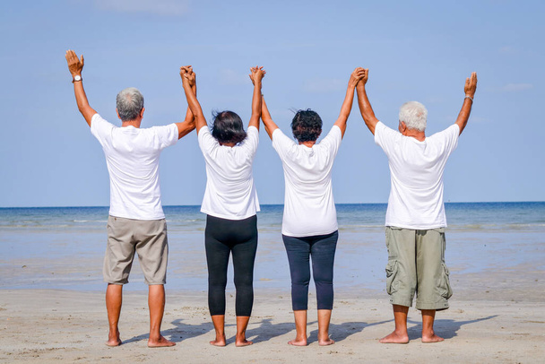 Onnellinen ryhmä vanhuksia ystäviä tulee lepäämään merellä Seisomassa, kädestä pitäen ja merelle päin - Valokuva, kuva