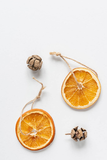 Christmas toys made of dried oranges and juniper cones on a string and rope. Background for greeting cards with copy space. - Photo, Image