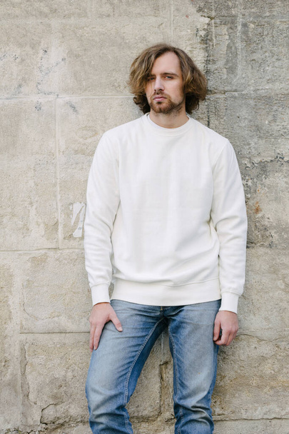 Man wearing white sweatshirt or hoodie for mock up, logo designs or design prints with with free space among europe city streets. - Foto, immagini