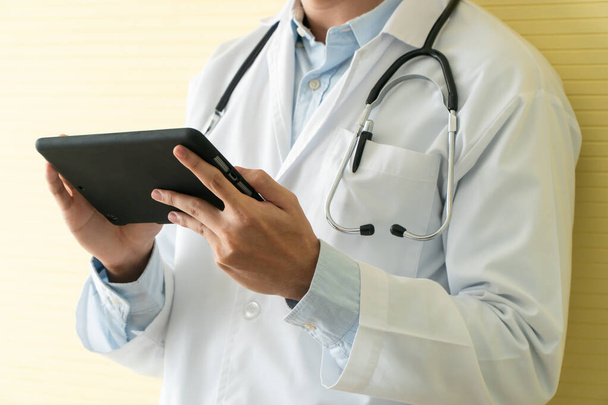 Jonge Aziatische artsen die tabletten gebruiken om gegevens en informatie te controleren voor het gezondheidsonderzoek van patiënten. Concept van digitale technologie en communicatie voor de medische sector. - Foto, afbeelding