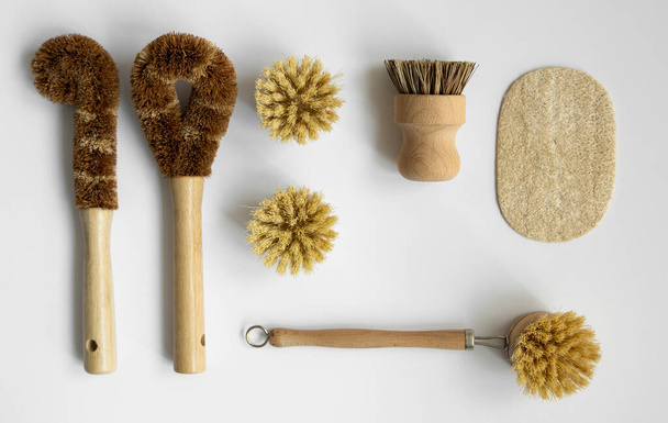 Set of brushes for eco-cleaning the home, washing dishes and surfaces without chemicals on a gray surface. Zero waste kitchen cleaning concept. Eco friendly natural cleaning bamboo dish brushes. - 写真・画像