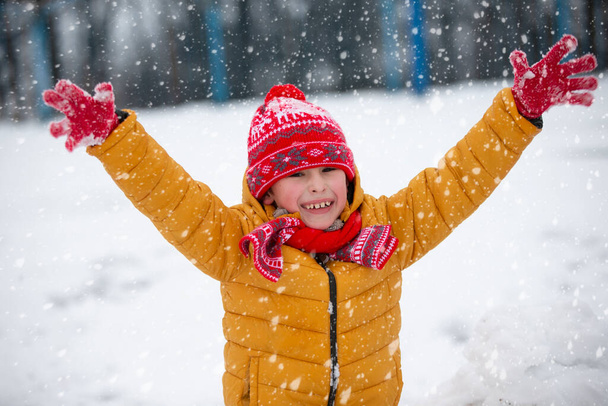 Παιδί το χειμώνα. Ευτυχισμένο αγόρι με φωτεινά ρούχα μια χειμωνιάτικη μέρα. - Φωτογραφία, εικόνα