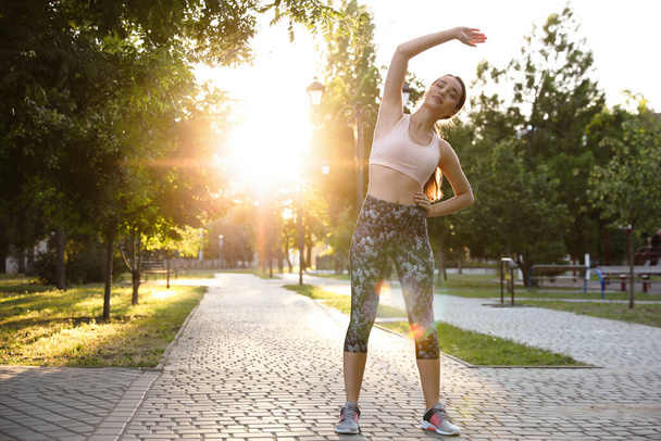 Young woman stretching before morning run in park. Space for text - Photo, Image