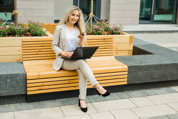 beautiful young female in suit with laptop and phone - Foto, imagen