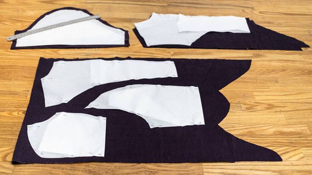 papírové rozvržení šicích vzorů šatů na fialové tkanině na dřevěném stole doma - Fotografie, Obrázek