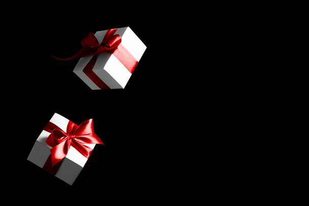 Kara Cuma alışverişi. Siyah arkaplandaki kırmızı kurdeleli beyaz hediyeler Kara Cuma afişi için. Uzayı kopyala Uçan fon - Fotoğraf, Görsel