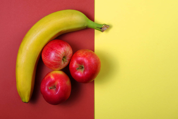 fondo de fruta de colores. plátano y manzanas en cartón de color. Vista superior. espacio de copia - Foto, Imagen