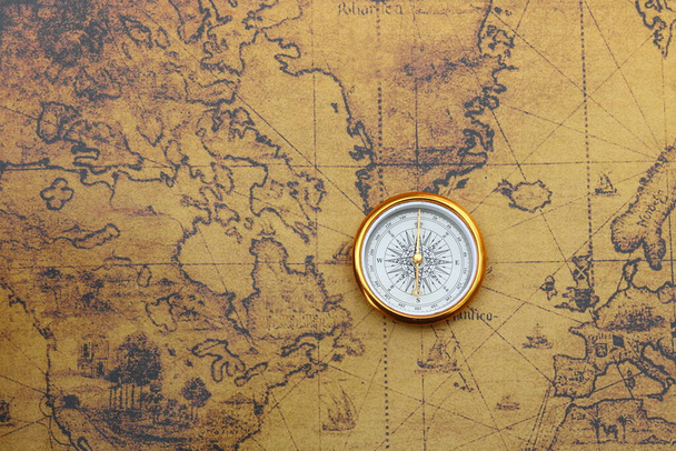 Klassischer runder Kompass auf dem Hintergrund einer alten historischen Weltkarte als Symbol des Tourismus mit Kompass, Reisen mit Kompass und Outdoor-Aktivitäten mit Kompass - Foto, Bild