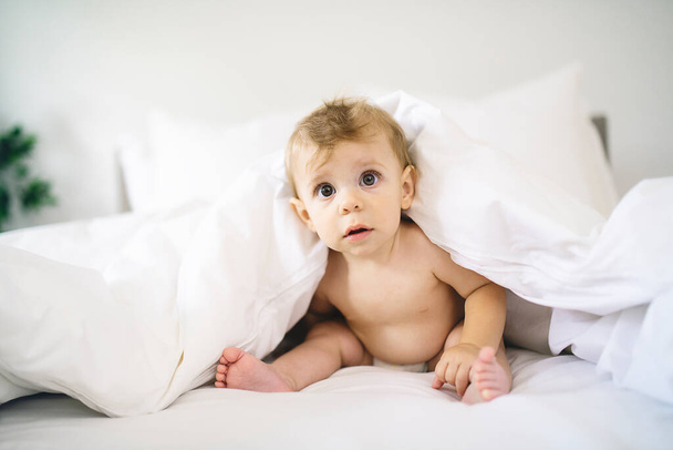 Cute happy baby girl in diaper on bed - Valokuva, kuva