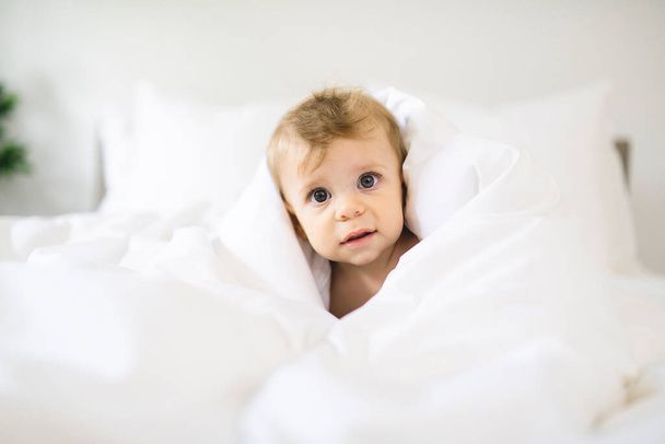 Cute happy baby girl in diaper on bed - Fotó, kép