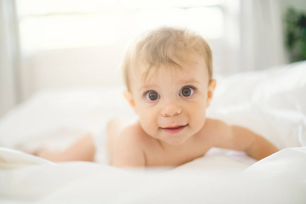 Cute happy baby girl in diaper on bed - Fotoğraf, Görsel