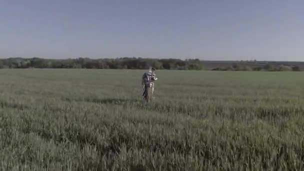 Een jongeman in een Israëlisch militair uniform bidt midden in een groen veld. Hij draagt tefilline en tallit. De drone beweegt eromheen. - Video