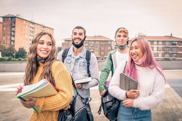 Education, healthcare and pandemic concept - Group of universitary students wearing face protective medical masks for protection from virus disease with backpacks walking and talking outdoors - Foto, Imagem