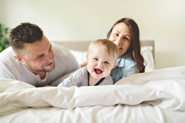 happy family mother, father and son at home in bed - Φωτογραφία, εικόνα