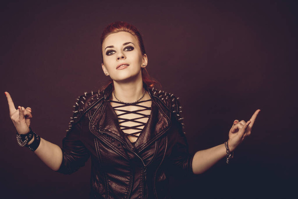 Portrait of a young punk woman with dark leather jacket isolated in studio on black background. - Фото, изображение