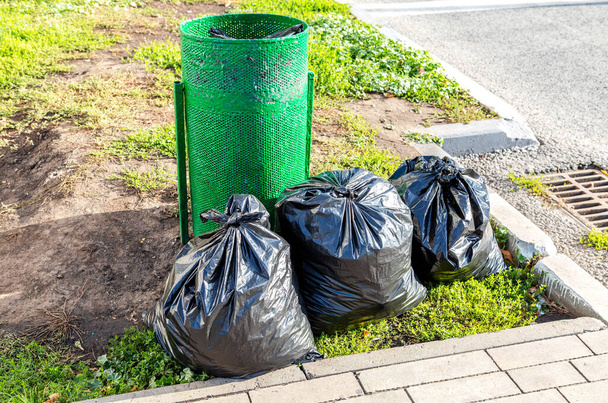Poubelle en métal et sacs poubelle en plastique dans la rue de la ville - Photo, image